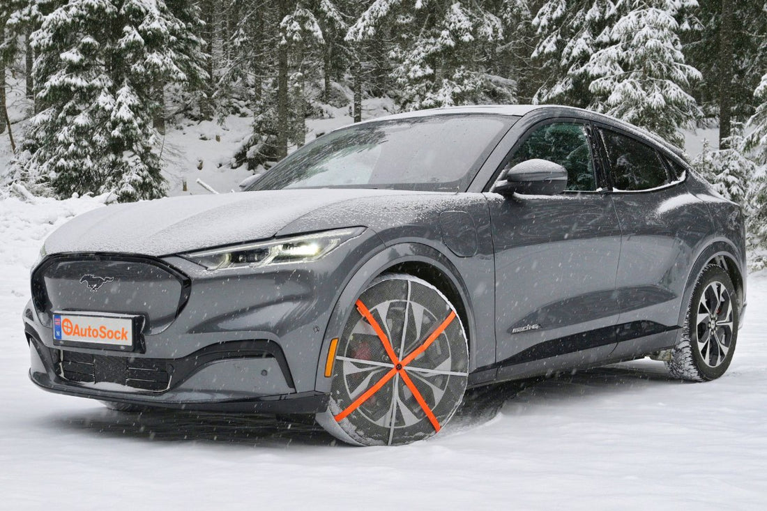 Tekstil snøkjeder installert på forhjulene til en elbil Ford Mustang mach-e som står på snø