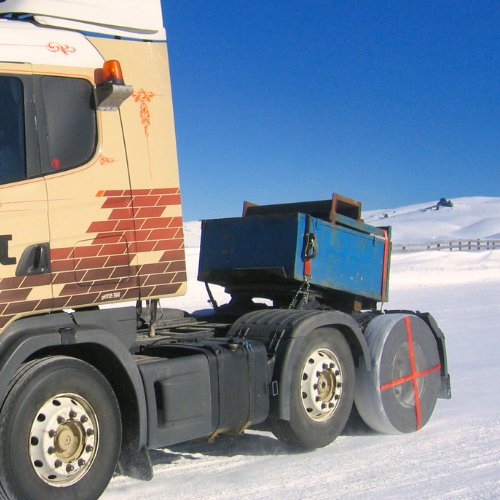 AutoSock tire sock mounted on truck wheel, driving on snow in winter landscape